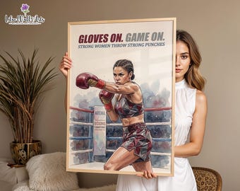 May include: A framed poster featuring a watercolor illustration of a boxer in a ring. The text reads GLOVES ON. GAME ON. STRONG WOMEN THROW STRONG PUNCHES. The boxer wears red gloves and a geometric patterned sports bra and shorts set.