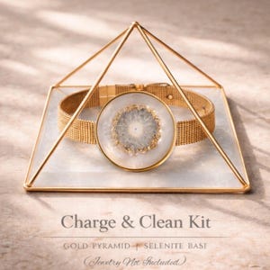 May include: A gold-colored pyramid-shaped display case with a white and gold base, holding a gold mesh bracelet and a white and gray circular stone. The text "Charge & Clean Kit" is displayed below the case.