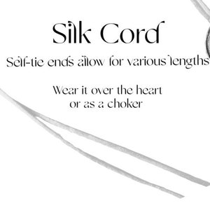 May include: A white silk cord with self-tie ends. The text "Silk Cord" is written in a decorative font. The text "Self-tie ends allow for various lengths" and "Wear it over the heart or as a choker" is also written on the image.