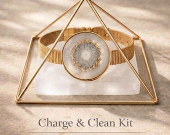 Puede incluir: Un marco de pirámide de metal dorado colocado sobre una base rectangular de selenita blanca. El texto Charge & Clean Kit, Gold Pyramid | Selenite Base y Jewelry Not Included está impreso debajo del objeto en la superficie.