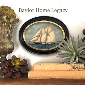 May include: A framed oval painting of a sailboat with white sails on a blue body of water. The frame is black with gold accents. The painting is titled "Baylor Home Legacy".