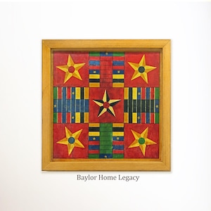 May include: A square wooden board game with a light wood frame featuring a red background, four large yellow stars in the corners, and a central star. The board includes paths of blue, yellow, green, and red rectangular segments. Text reads Baylor Home Legacy.