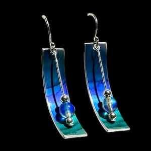 Peut inclure: Une paire de boucles d'oreilles pendantes en argent avec émail bleu et vert et un accent de perle de verre bleue.