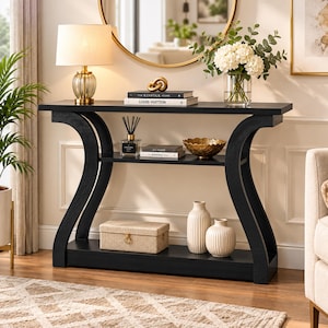 May include: A black console table with a rectangular top, a middle shelf, and a bottom shelf, supported by two curved side legs. The table features a smooth finish and a multi-tiered design, providing open storage space for decorative items.