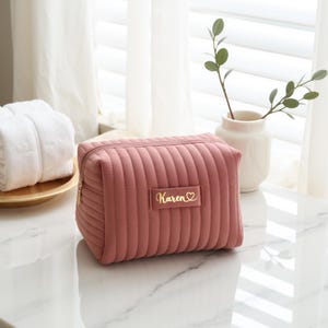 a pink cosmetic bag sitting on top of a white counter