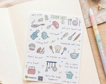 May include: A white sticker sheet featuring various kitchen-themed illustrations including a toaster, pots, pans, a chef hat, and utensils. The sheet includes text phrases such as "let's cook!", "eat your heart out", "just beat it!", "cooking time!", "homemade with love", "that's my jam!", "my kitchen my rules", "we're toast!", "life is short, lick the bowl", "where the magic happens!!", and "cooking is love".