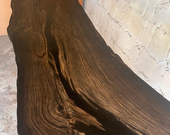 Black oak table with cavities filled with black resin, natural edge