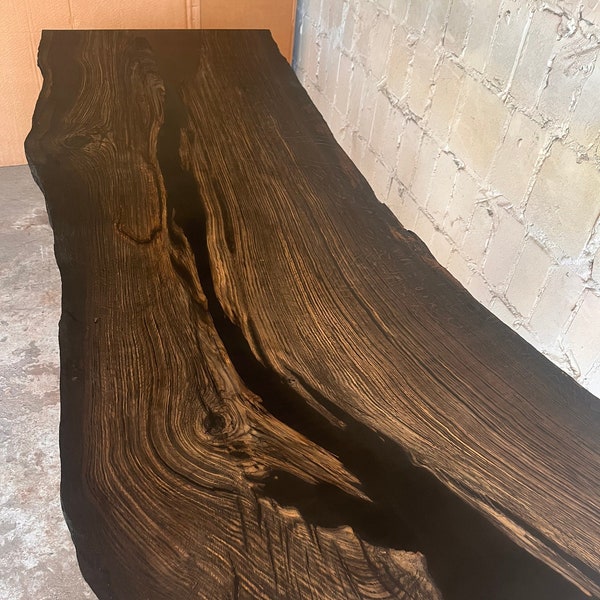 Black oak table with cavities filled with black resin, natural edge