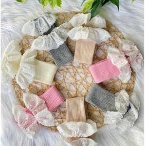 Könnte beinhalten: Sechs Paar Kniestrümpfe mit weißer Spitzenborte. Die Strümpfe sind in verschiedenen Farben, darunter rosa, beige und grau.