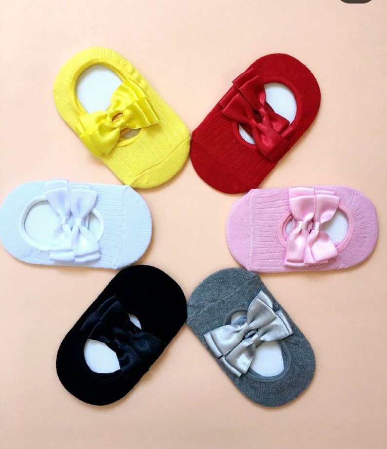 K&ouml;nnte beinhalten: Sechs Paar F&uuml;&szlig;linge in verschiedenen Farben: Gelb, Rot, Hellblau, Rosa, Schwarz und Grau. Jede Socke hat eine Satinschleife in einer passenden oder komplement&auml;ren Farbe. Die Socken sind f&uuml;r das Tragen mit Ballerinas oder anderen Schuhen mit niedrigem Schnitt konzipiert.