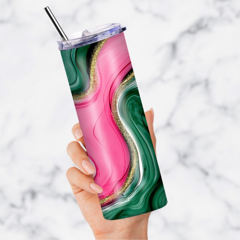 May include: A stainless steel tumbler with a green and pink marble design and gold glitter accents. The tumbler has a clear lid and a straw.