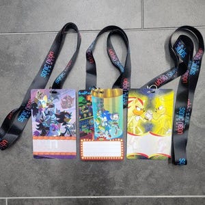May include: Several lanyards with colorful event badges featuring Sonic the Hedgehog characters. The badges have various designs, including illustrations of Sonic, Shadow, and other characters. The black lanyards have "SONIC NEON" text.