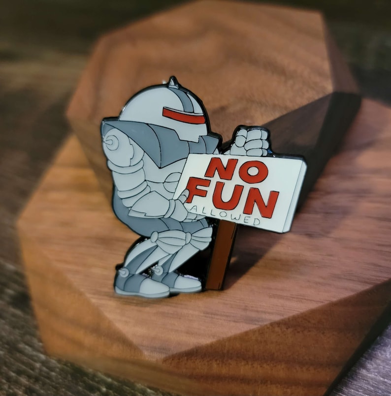 May include: A silver robot holding a white sign with the words 'NO FUN ALLOWED' in red letters.