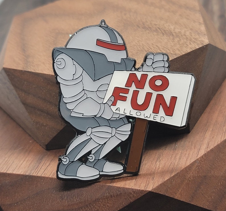 May include: A silver robot holding a white sign that says 'NO FUN ALLOWED' in red letters. The robot is wearing a gray helmet with a red visor.