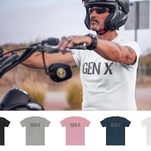 以下が含まれることがあります： 黒い文字で「GEN X」とプリントされた白いTシャツ。モデルがバイクのヘルメットをかぶり、バイクに乗っている姿でTシャツが紹介されています。Tシャツは、黒、杢グレー、ピンク、ネイビー、白の5色展開です。