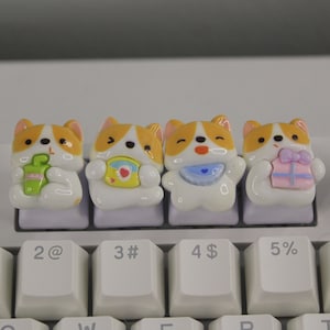 May include: Five adorable cartoon corgi keycaps in different colors with various accessories, including a cup of coffee, a gift box, a bib, and a drink. The keycaps are on a white keyboard.