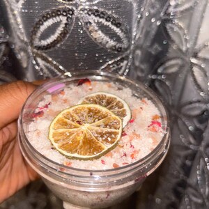 May include: A clear glass jar filled with pink bath salts, dried rose petals, and two dried lime slices.