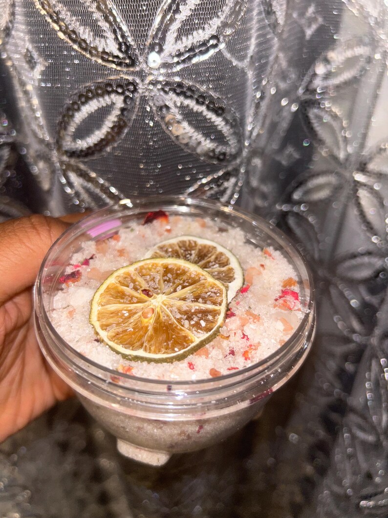 May include: A clear glass jar filled with pink bath salts, dried rose petals, and two dried lime slices.