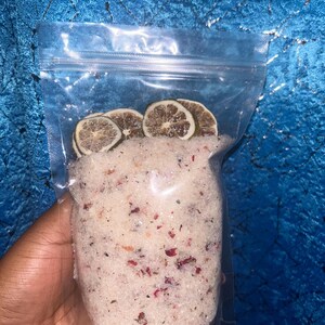 May include: A clear plastic bag filled with white bath salts with dried rose petals and lime slices.