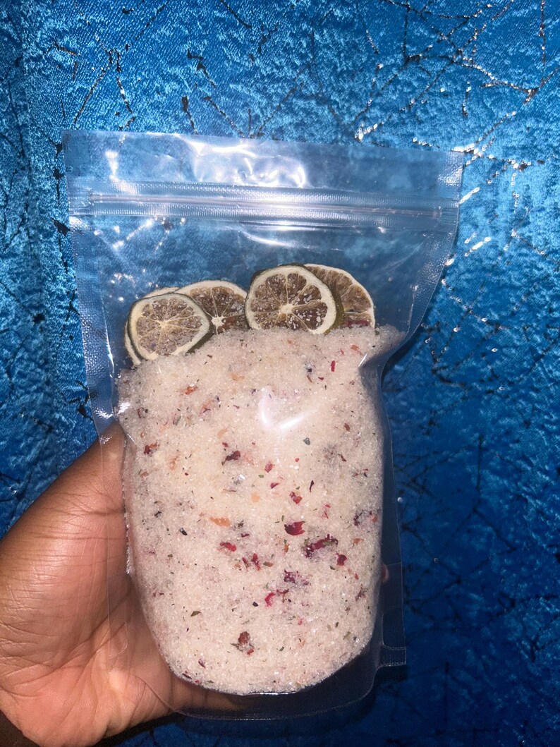 May include: A clear plastic bag filled with white bath salts with dried rose petals and lime slices.