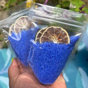 May include: Two clear plastic bags filled with blue bath salts and dried lime slices.
