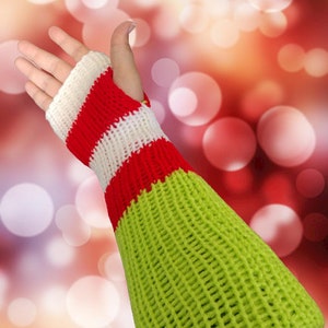 May include: A knitted arm warmer in green, red, and white. The wrist section features red and white stripes, while the arm portion is a vibrant green. The open-palm design allows for finger movement, suitable for cold weather.