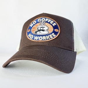 May include: A brown trucker cap with a white mesh back. The front has a circular patch with the words "NO COFFEE NO WORKEE" around a coffee cup design in blue, orange, and brown.