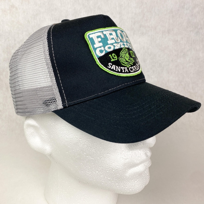 May include: Black and grey trucker hat with a green, white, and blue embroidered patch that says "Frog  Company 19 Santa Cruz".