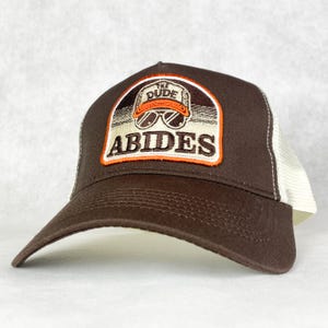 The Dude Abides inspiriert von The Big Lebowski Trucker Hat Cap mit Ultra Retro gesticktem Patch - coole Baseballkappe mit Netzrücken - braun /creme