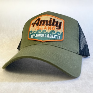 May include: A green and black trucker hat with an embroidered patch that says "Amity Island 50th Annual Regatta".