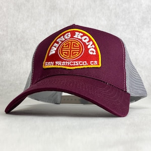 May include: A burgundy and gray trucker hat with a red, yellow, and white embroidered patch that says "Wing Kong San Francisco, CA" with a stylized Chinese symbol.