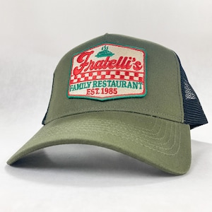 May include: A green and black trucker hat with an embroidered patch that says "Fratelli's Family Restaurant Est. 1985" in red, white and green.