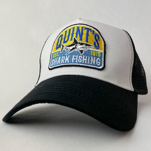 May include: White and black trucker hat with a blue, yellow and white embroidered patch that says "Quint's Shark Fishing Est. 1975".