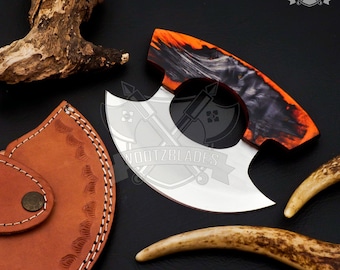 Könnte beinhalten: Ein silbernes und schwarzes Messer mit einem einzigartigen Griff aus orangefarbenem, schwarzem und weißem Holz. Das Messer hat eine gebogene Klinge und ein Loch im Griff. Das Messer wird mit einer braunen Lederscheide und zwei Geweihstücken gezeigt.