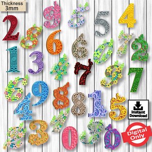 Puede incluir: Un conjunto de 15 números coloridos y diseñados con intrincados patrones florales. Los números tienen 3 mm de grosor y son perfectos para proyectos de manualidades. Los números están dispuestos en una cuadrícula sobre un fondo de madera blanca. El texto "Descarga instantánea" y "Solo digital" es visible en la imagen.