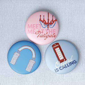 May include: Three circular pin-back buttons. The top pink button features a red chandelier graphic and the text "MEET ME AT THE Tailgate". The bottom left blue button shows a red archway. The bottom right light blue button features a red telephone booth and the text "Oxford IS CALLING".