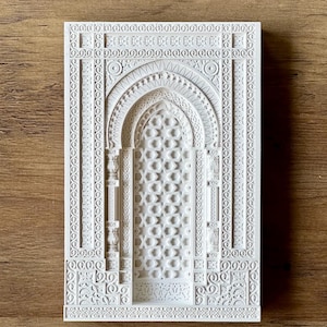 May include: White decorative wall art featuring an intricate, carved design of an arched doorway with geometric patterns. The design is reminiscent of traditional Islamic architecture.