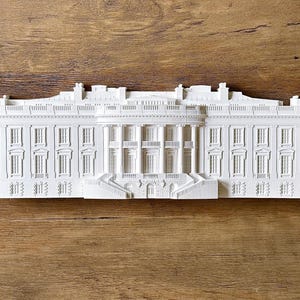 May include: A white model of the White House, a famous building in Washington, D.C., with a detailed facade and multiple windows.