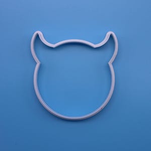 May include: White plastic cookie cutter shaped like a cartoon devil with horns.