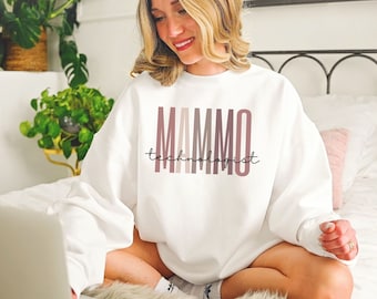 May include: A white sweatshirt with the text "MAMMO technologist" in a gradient of pink and brown. The sweatshirt is a crew neck style and appears to be made of a soft material. The text is centered on the front of the shirt.