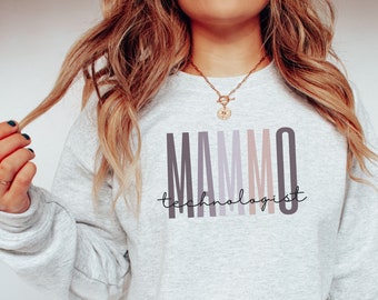 Puede incluir: Una sudadera gris con el texto "MAMMO technologist" impreso en la parte delantera en un estilo de letras en bloque verticales y de colores.