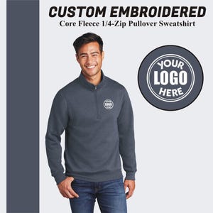 May include: A dark blue 1/4-zip pullover sweatshirt with a mock neck and a zipper that extends to the chest. The sweatshirt has a white embroidered logo that says "YOUR LOGO HERE".