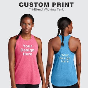May include: Two women's athletic tank tops with a racerback design. The tank top on the left is pink and the tank top on the right is blue. Both tank tops have the text "Your Design Here" printed on the front.