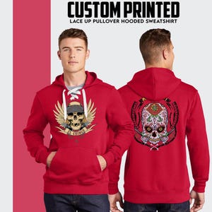 Puede incluir: Sudadera roja con capucha y cord&oacute;n de ajuste con un gr&aacute;fico de calavera en la parte delantera y un gr&aacute;fico de calavera de az&uacute;car en la parte trasera. El texto "El Gringo" est&aacute; impreso debajo de la calavera en la parte delantera.