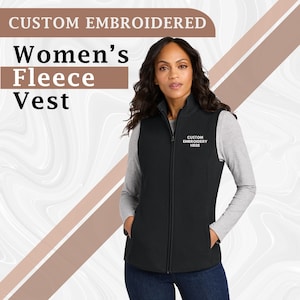 May include: Black fleece vest with a full-length zipper and two front pockets. The vest has the text "CUSTOM EMBROIDERY HERE" embroidered on the chest. The top of the image reads "CUSTOM EMBROIDERED" and "Women's Fleece Vest".