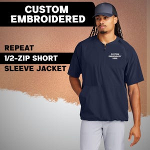 May include: Navy blue 1/2-zip short sleeve jacket with the text "CUSTOM EMBROIDERY HERE" embroidered on the chest. The jacket has a front pocket and a drawstring hem. The text "CUSTOM EMBROIDERED" and "REPEAT 1/2-ZIP SHORT SLEEVE JACKET" are displayed on the left.