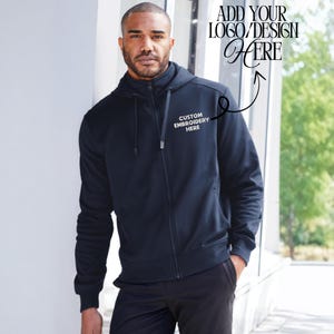 Pode incluir: Um casaco com capuz azul marinho com z&iacute;per com o texto "CUSTOM EMBROIDERY HERE" em branco. O casaco com capuz tem um capuz e um fecho de correr. A imagem tamb&eacute;m inclui o texto "ADD YOUR LOGO/DESIGN HERE".