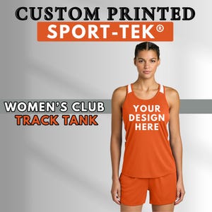 May include: An orange track tank top and shorts set with white accents. The tank top has the text "YOUR DESIGN HERE" printed on the front. The image also includes the text "CUSTOM PRINTED SPORT-TEK" and "WOMEN'S CLUB TRACK TANK".