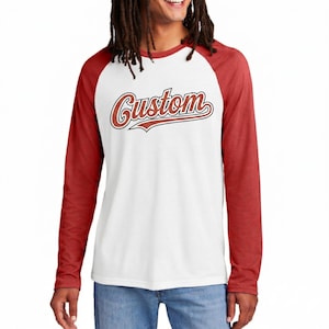 May include: A long-sleeved baseball style shirt with a white body and red sleeves. The word "Custom" is printed across the chest in a script font with a red and white outline.