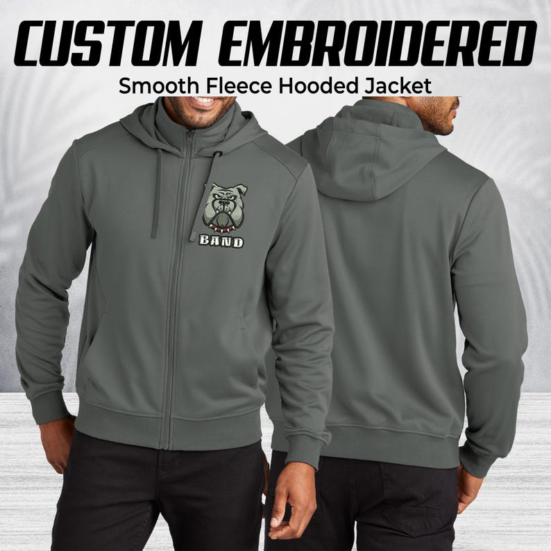 Pode incluir: Casaco cinzento com capuz em fleece liso com fecho de correr completo e capuz. O casaco apresenta um gr&aacute;fico de bulldog bordado com a palavra "BAND" por baixo. O texto "CUSTOM EMBROIDERED" est&aacute; na parte superior da imagem.